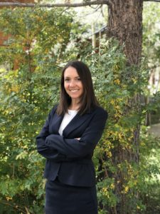Photo of Sophie Bidet, Mammoth Lakes attorney, wearing a suit standing in front of a tree smiling with her arms crossed